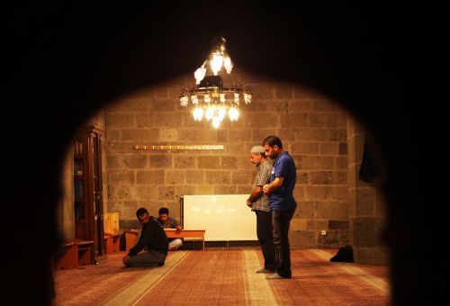 Free A serene scene of men praying inside a mosque in Erzurum, Türkiye, captured in warm lighting. Stock Photo