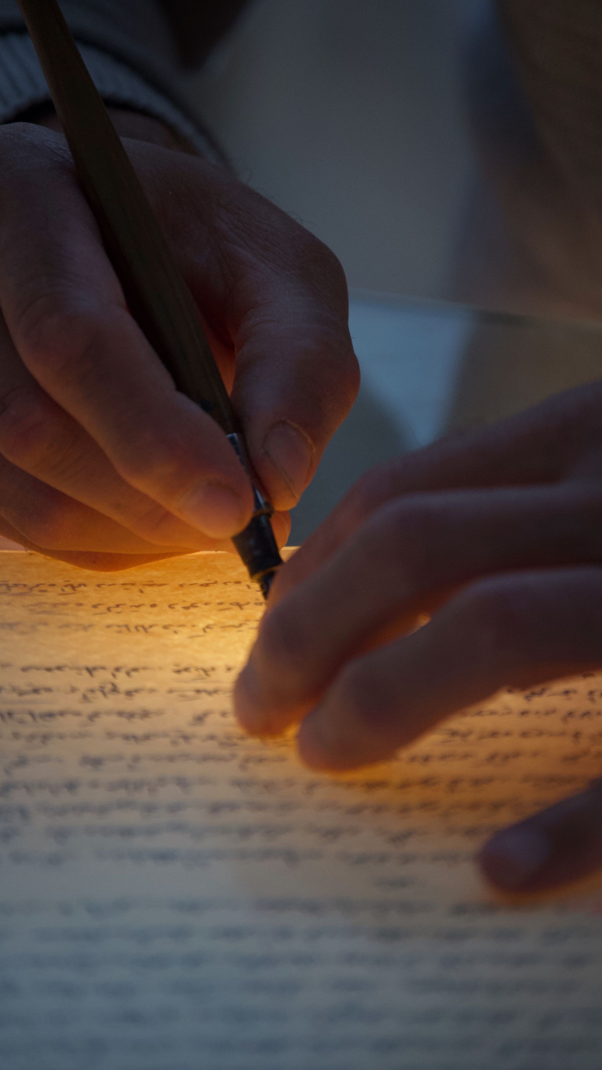 A sofer's hands writing with a quill on parchment