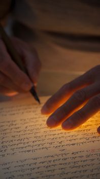 A hand writing on illuminated paper with warm, dramatic lighting effects.