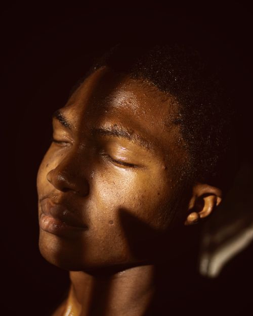 Free A thoughtful portrait of a man with eyes closed, bathed in dramatic warm sunlight. Stock Photo