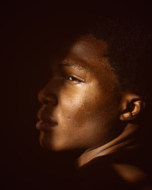 Free A close-up portrait of a man in dramatic lighting highlighting his profile and textures. Stock Photo