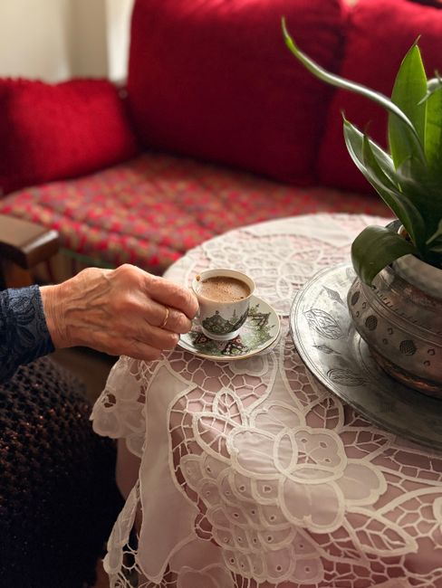 A warm moment capturing a hand holding coffee on a lace-covered table indoors.