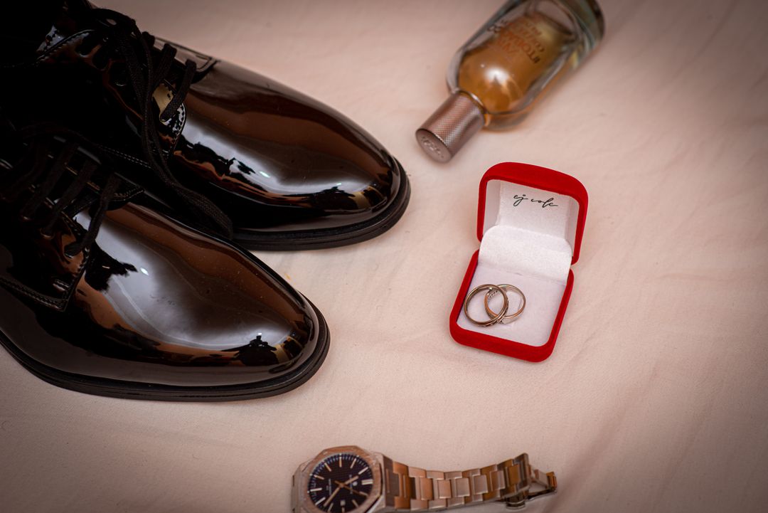 how much should a wedding ring cost — groom flat-lay with plain gold bands, dress shoes and watch — FoundryCut
