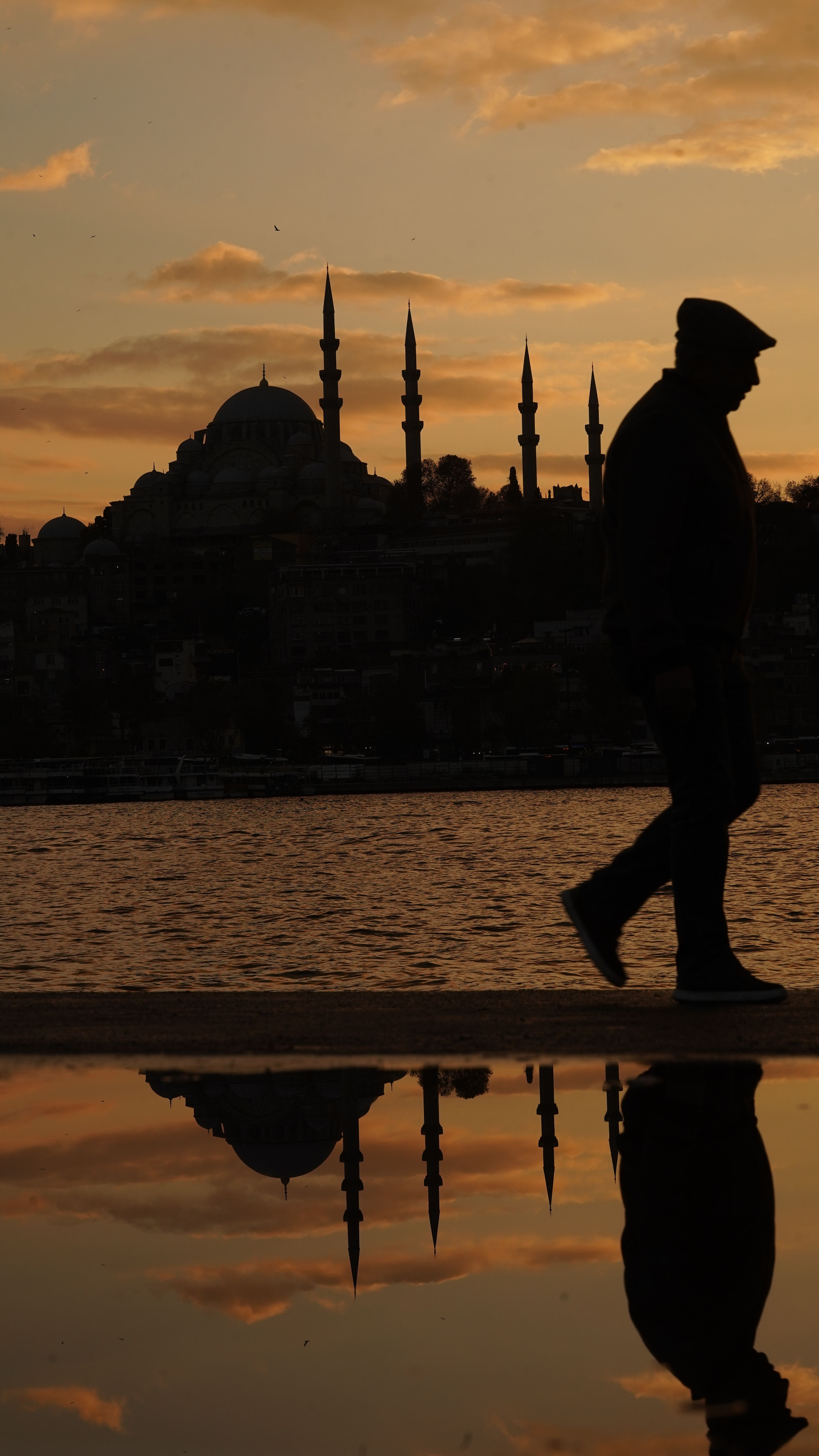 A silhouette of a man walking near Suleymaniye Mosque during sunset.