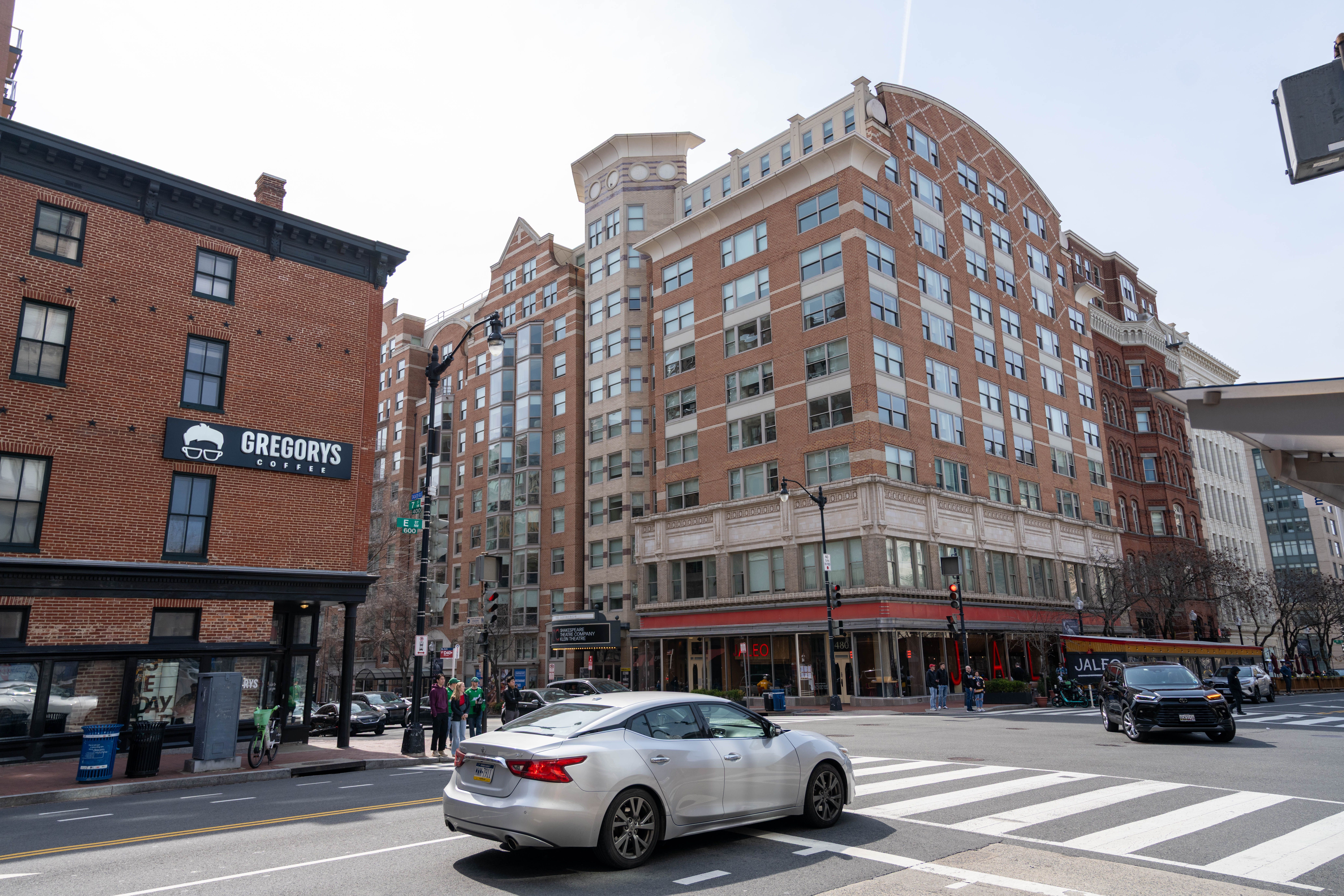 Busy urban street scene in Washington, D.C. with Gregorys Coffee and cars on a sunny day.