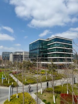 Contemporary office buildings surrounded by a landscaped urban park under a clear blue sky.