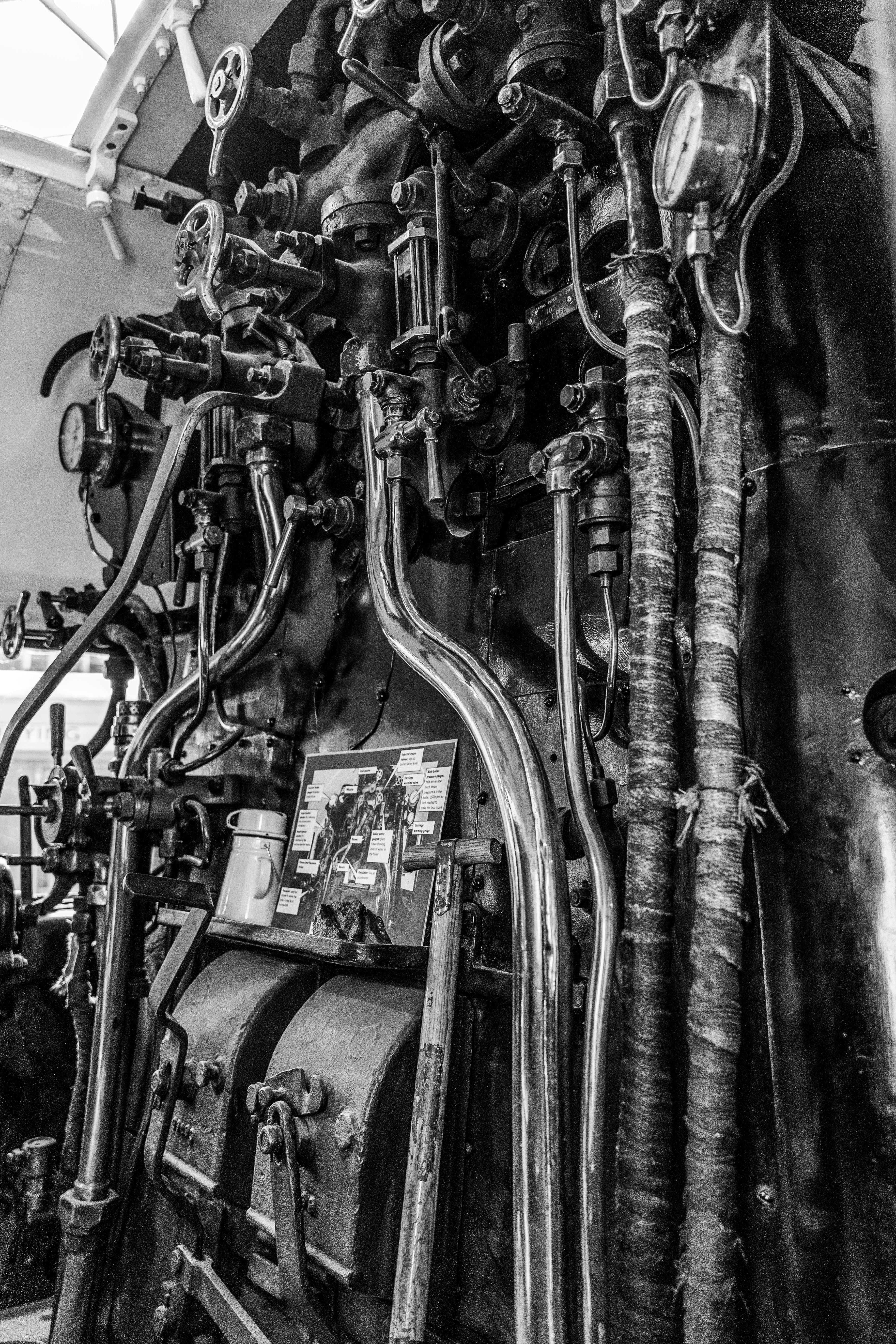 Black and white photo showing intricate steam train controls and gauges.