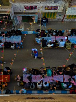 A vibrant outdoor street gathering with people dining together under festive decorations.