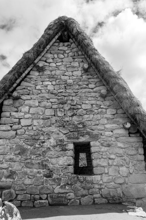 Free Black and white photo of an ancient stone building with thatched roof in Cusco, Peru. Stock Photo