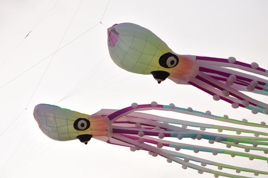 Vibrant octopus-shaped kites flying against a clear sky, creating a whimsical scene.