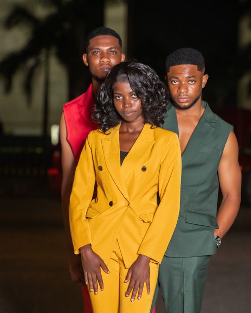 Free Group of fashionable adults in colorful suits posing confidently at night. Stock Photo
