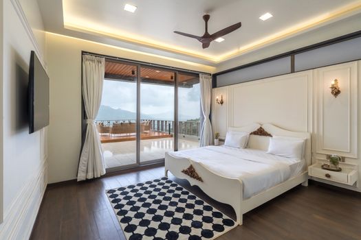 Spacious modern bedroom featuring a double bed, checkered rug, and scenic balcony view, perfect for luxury living.