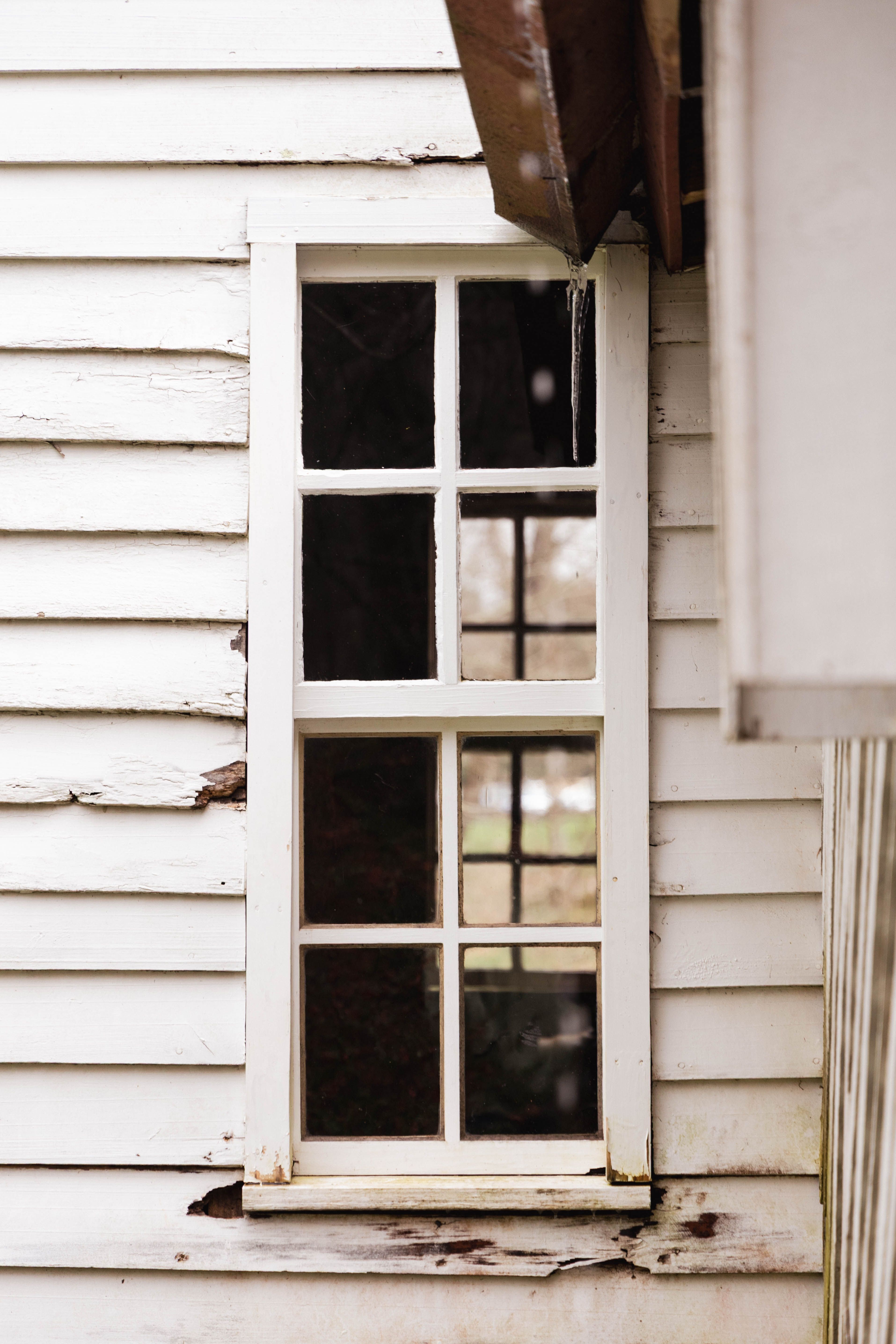 Close-up of a rustic window frame on a weathered wooden house exterior, showcasing vintage charm.