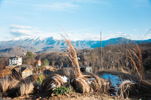 Free Picturesque landscape of snow-covered mountains, countryside homes, and dry grass in early winter. Stock Photo