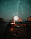 Person Standing on Rock Near Body of Water during Night Time