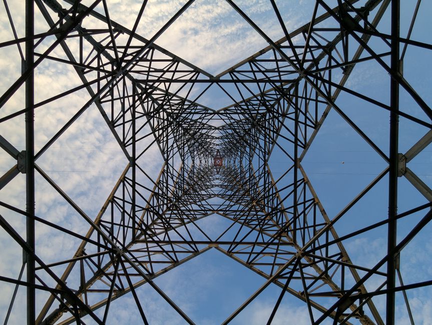 Looking up through a steel power tower against a blue sky and clouds. Looking up through a steel power tower against a blue sky and clouds.