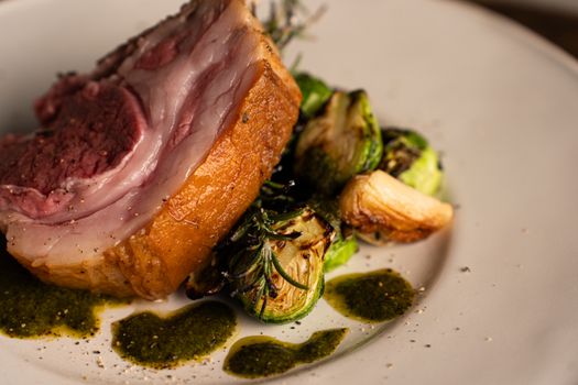 A close-up of gourmet roasted lamb served with Brussels sprouts and rosemary in a fine dining setting.