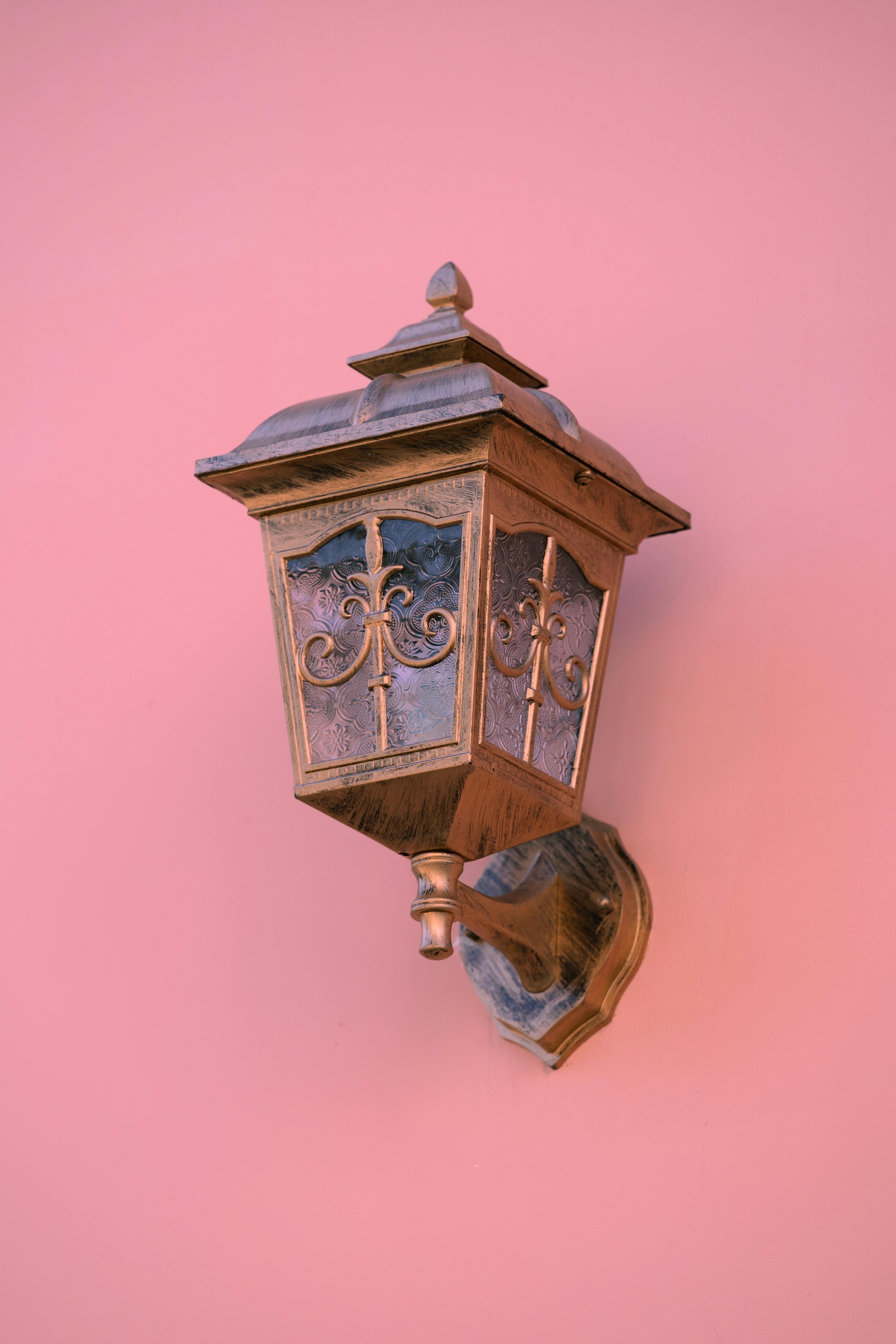 Elegant vintage lantern mounted on a pink wall, showcasing classic design.