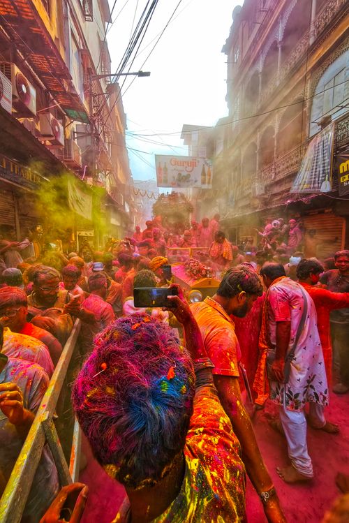 Free Colorful Holi celebration on the streets of Kolkata, India, with people covered in vibrant powders. Stock Photo