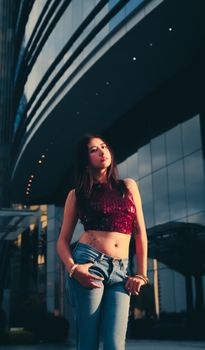 Young woman in trendy attire posing confidently outside a sleek city architecture.