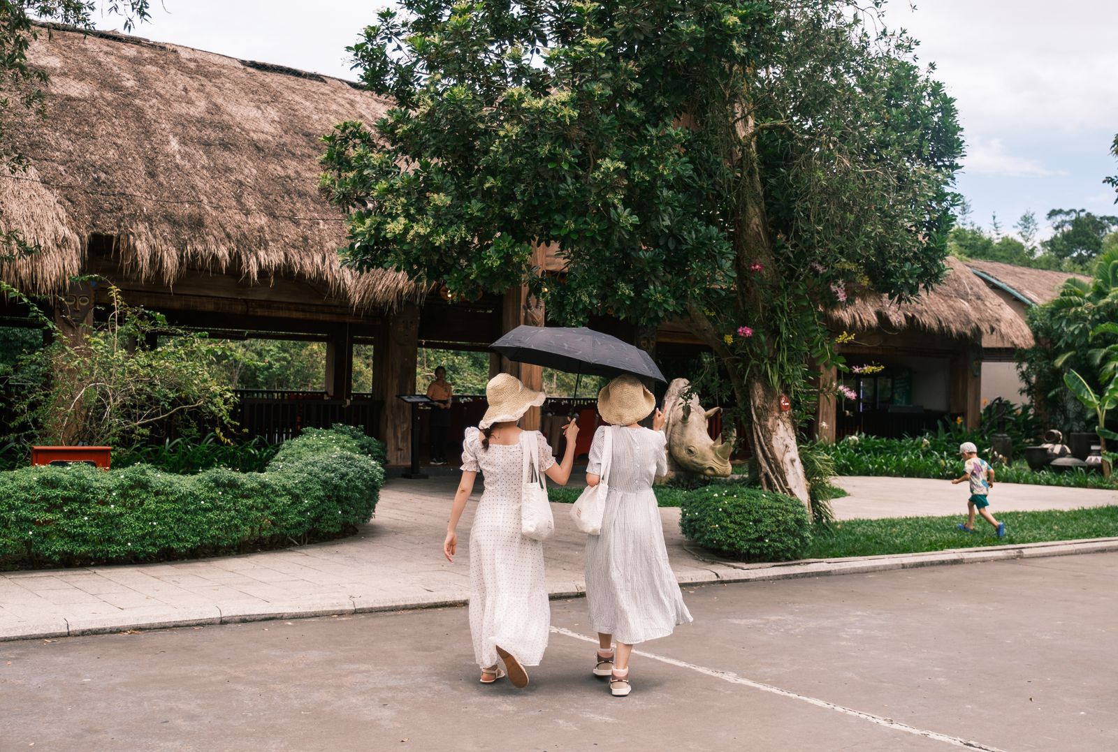Women wearing elegant white resort dresses while walking through a tropical resort