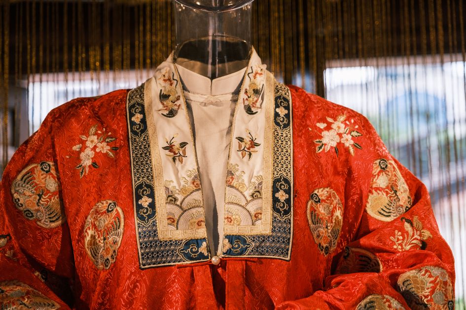 Close-up of an ornate traditional Chinese robe with intricate embroidery on display, showing the layered floral motifs that define Ming Dynasty needlework tradition.