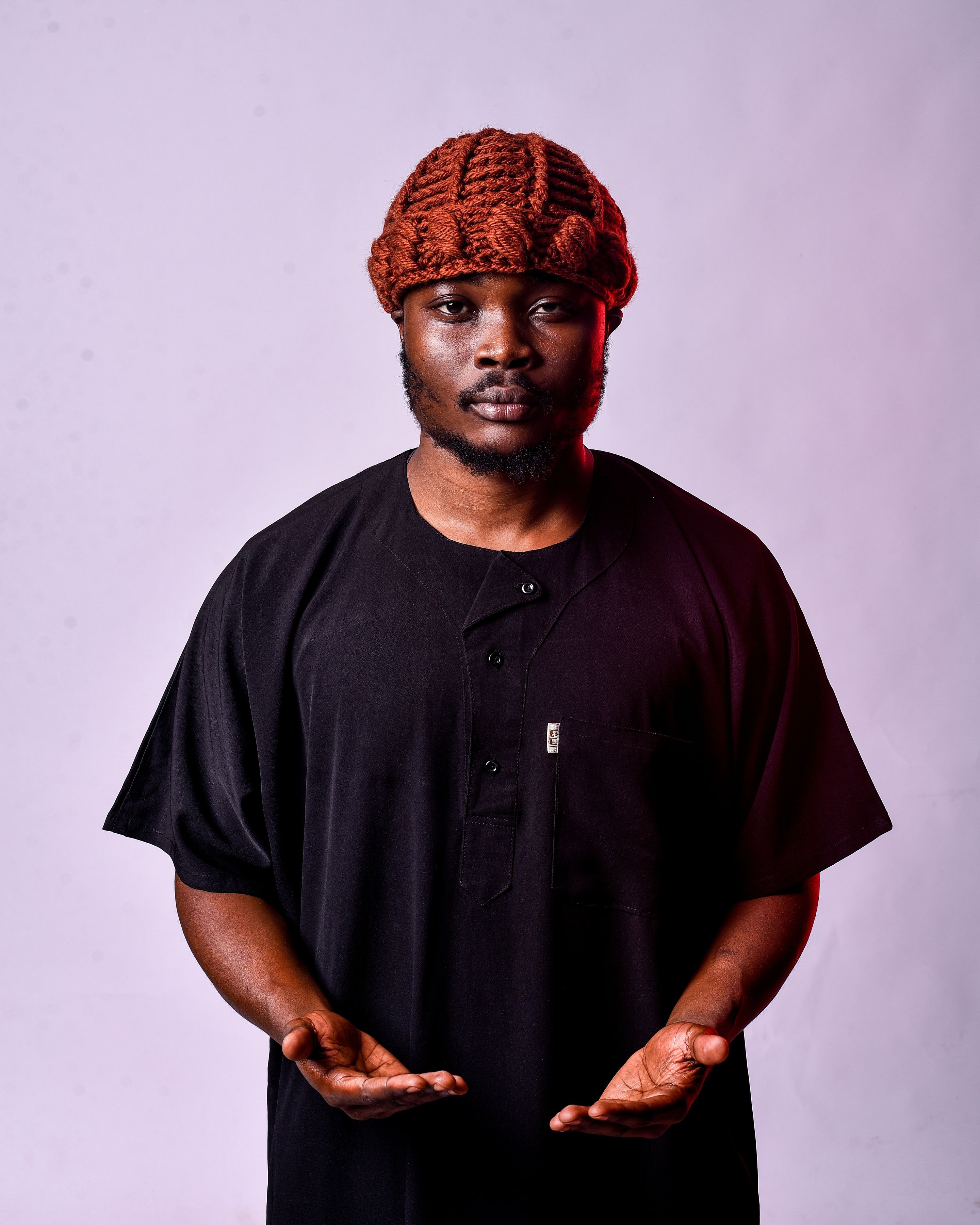 A man wearing traditional African attire poses confidently with a neutral background.