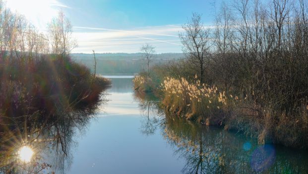 Tranquil winter river scene with trees and sunlit reflections.