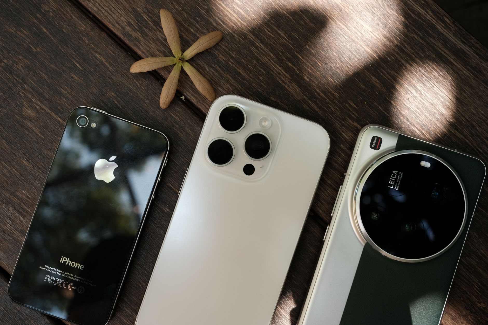 Collection of three modern smartphones displayed on a wooden table surface.
