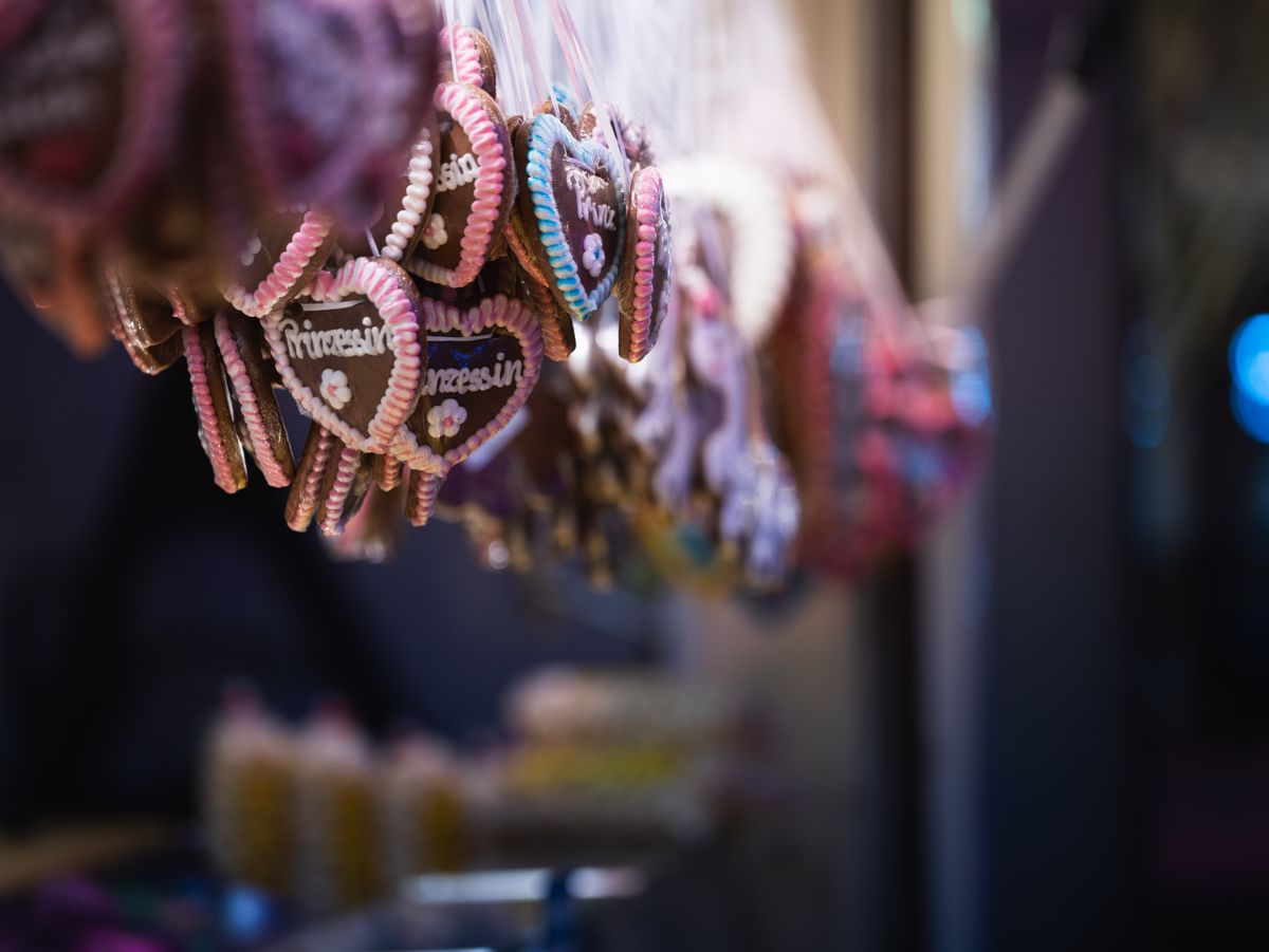 Close-up of hanging gingerbread hearts with colorful icing at a market stall.