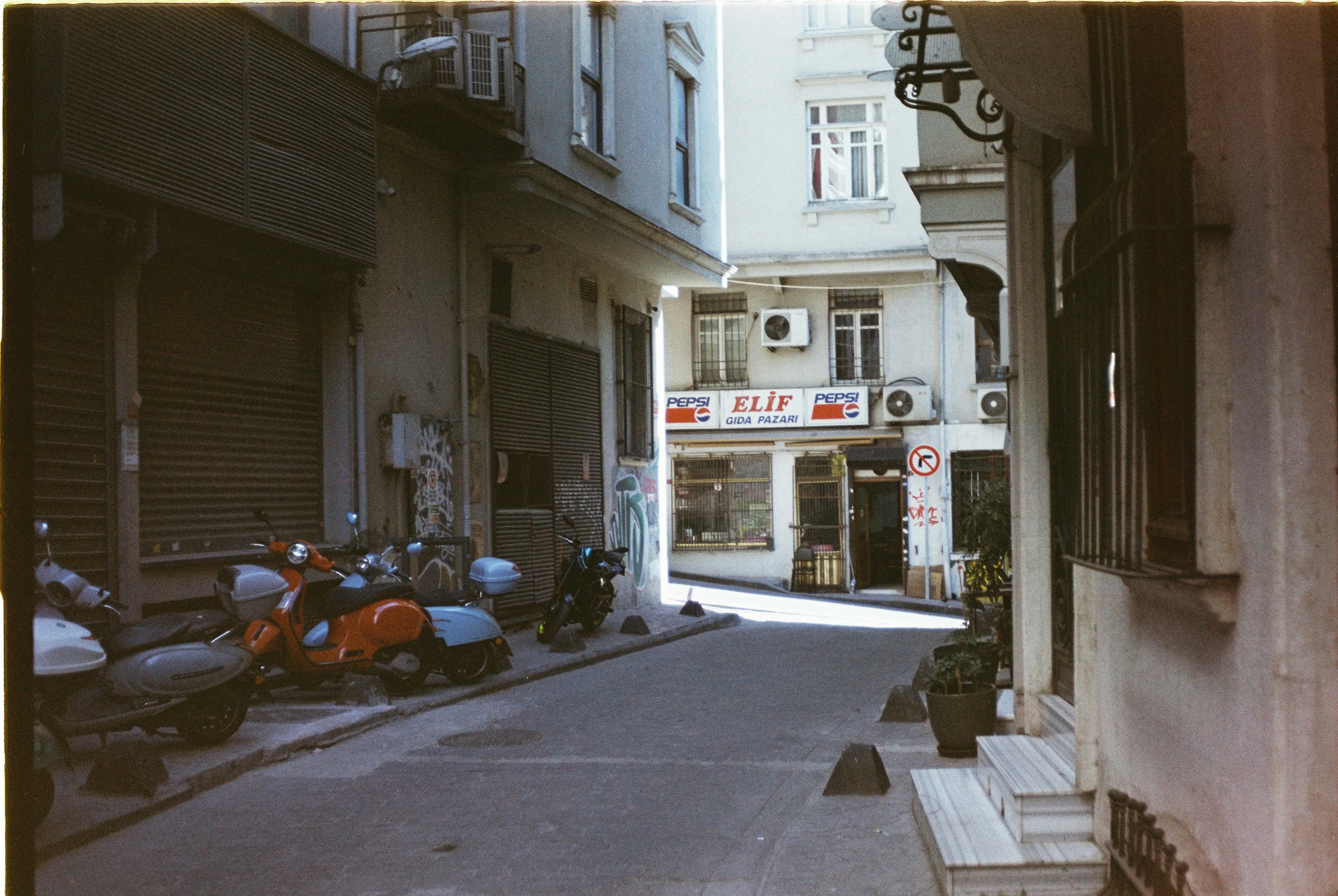 Explore a quaint Istanbul alley with scooters, vintage signage, and historical architecture.