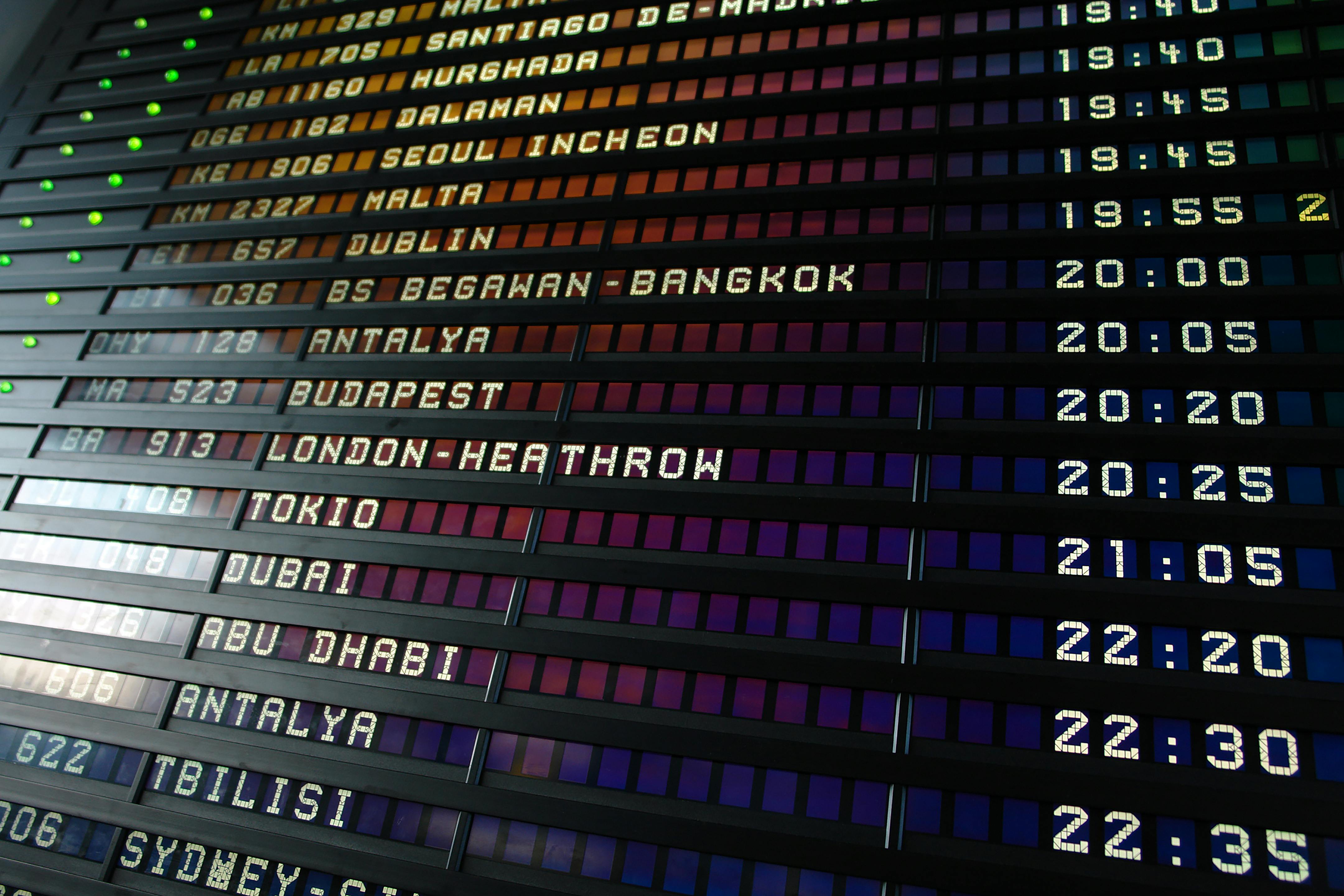 Airport departure board displaying flight destinations and scheduled times in rows.