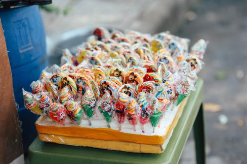 Free Vibrant assortment of wrapped lollipops arranged on a street market stand, showcasing bright colors and fun patterns. Stock Photo