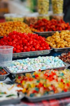 Vibrant market stall showcasing assorted candies and dried fruits in trays.
