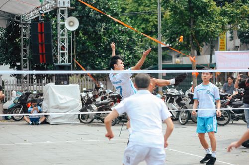 Free Men playing a dynamic match of sepak takraw in an outdoor urban environment. Stock Photo