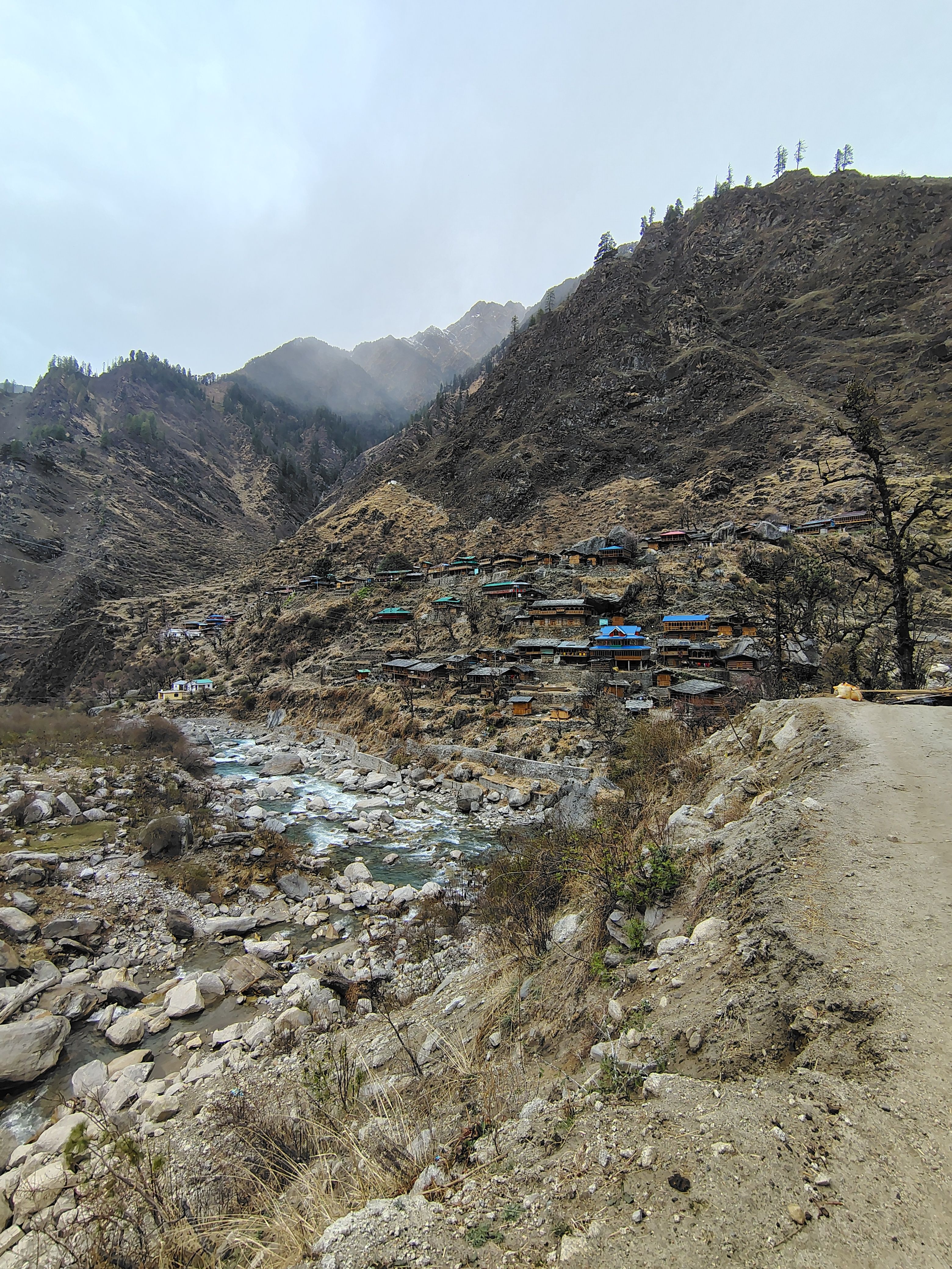 Capture of a remote mountain village alongside a river in Uttarakhand, India, showcasing natural beauty.