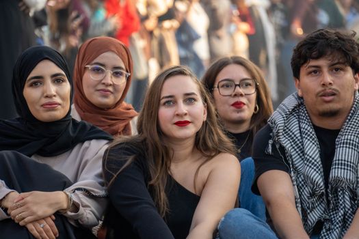 A diverse group of young adults sitting at an outdoor gathering, showcasing cultural diversity and friendship.