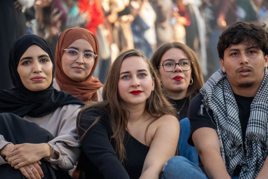 Un grupo diverso de jóvenes sentados en una reunión al aire libre, mostrando diversidad cultural y amistad.