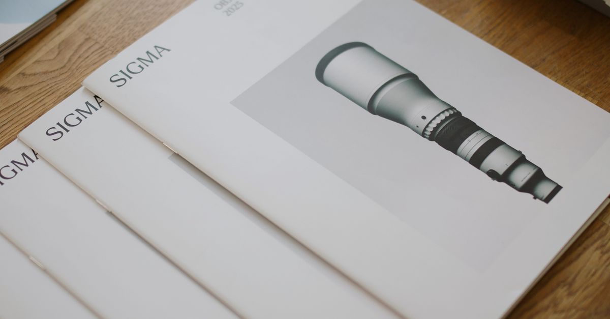 Arranged Sigma lens brochures on a wooden table, showcasing lens specifications and design.