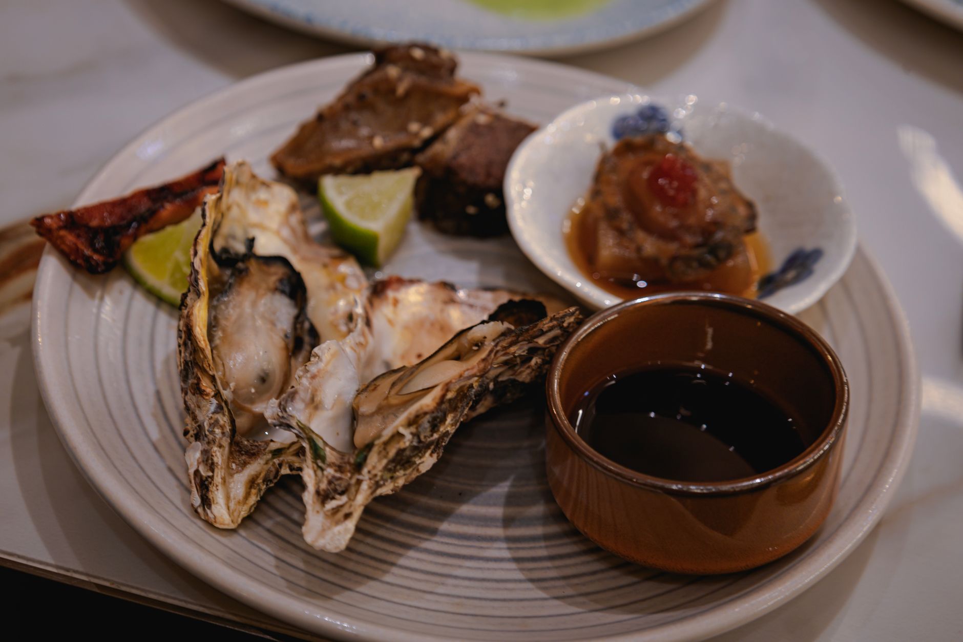 A delicious gourmet plate featuring fresh oysters, sliced lime, and dipping sauce.