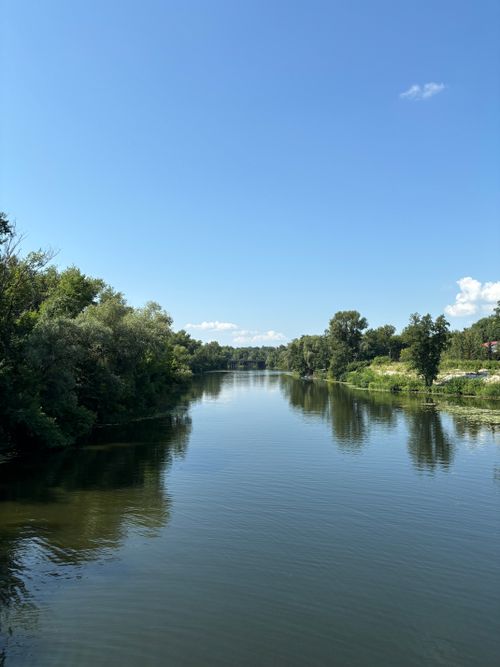 Free Serene river landscape with clear blue sky and surrounding lush greenery. Stock Photo