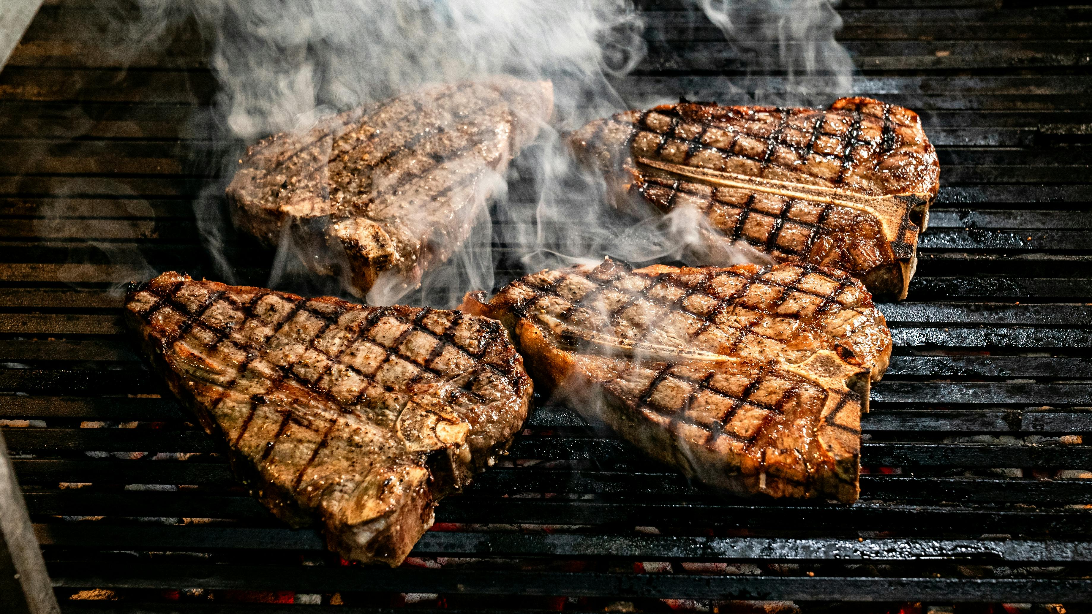 Large cut of meat being grilled over live fire BBQ