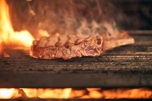 Close-up of a delicious steak being grilled over an open flame, emitting a mouth-watering aroma.