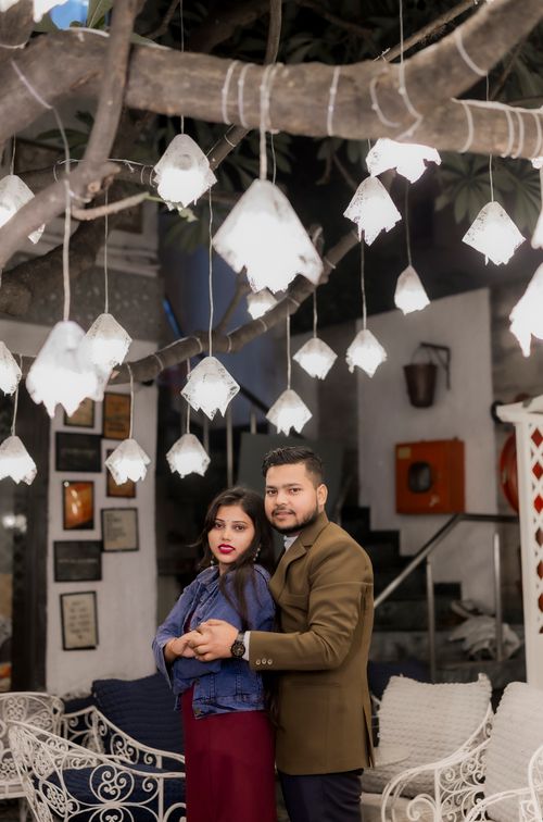 Free A stylish Indian couple poses under decorative lights, creating a romantic and elegant atmosphere outdoors. Stock Photo