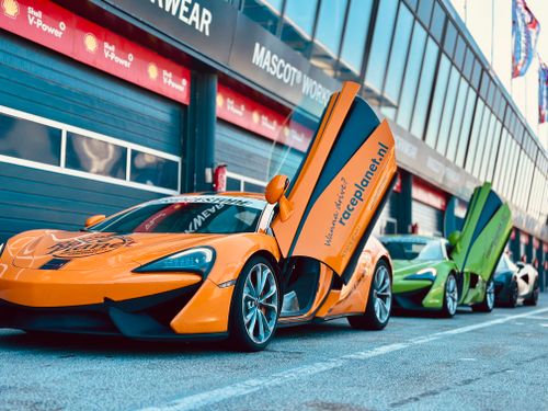 Free Vibrant sports cars with open doors parked at a professional racing circuit, exuding speed and luxury. Stock Photo