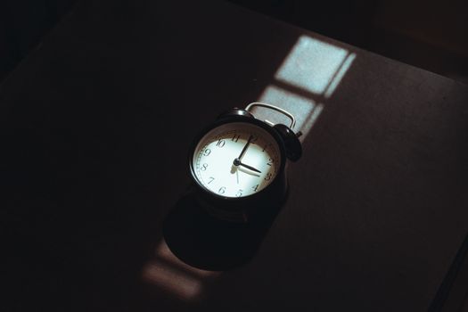 A nostalgic analog clock in moody shadows, capturing serene morning light.