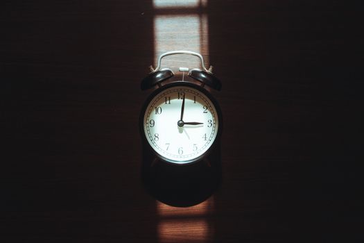 Classic vintage alarm clock with dramatic light and shadow play, evoking nostalgia and warmth.