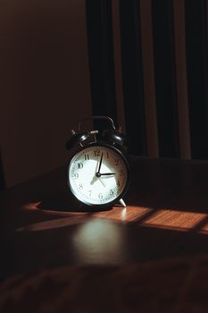 Retro analog alarm clock with artistic shadows in a sunlit room, evoking a nostalgic morning ambiance.