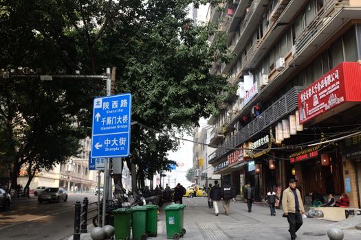 A busy street in China featuring signage, pedestrians, and diverse storefronts.