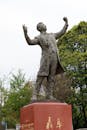 Statue of Man in Suit with Raised Arms Outdoors